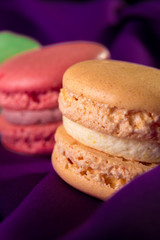 Three colorful macaroons on purple background. French dessert. Close up. Macro.
