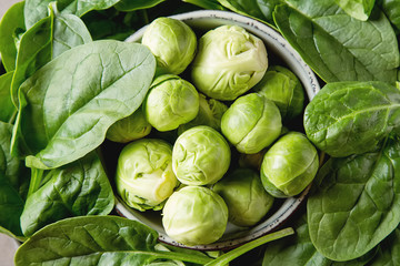 Washed fresh mini spinach and Brussels sprouts. Dark background.