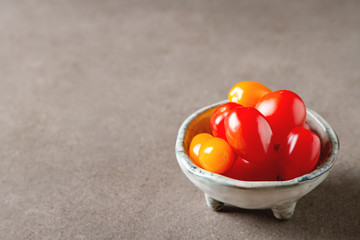 Fresh ripe cherry tomatoes in a ceramic bowl. Dark gray background.