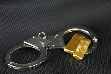 The chrome metal handcuffed and gold bar represent the crime fraud and punishment equipment concept...