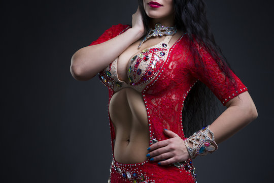 Exotic eastern women performs belly dance in ethnic red dress
