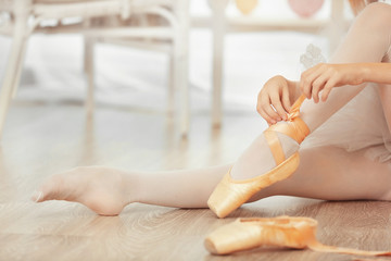Ballerina tying ballet shoes, closeup - obrazy, fototapety, plakaty