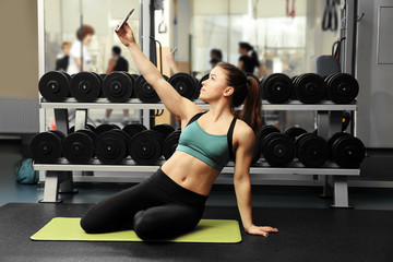 Fototapeta na wymiar Young attractive woman taking selfie in gym
