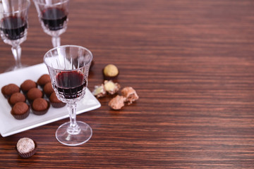 Glasses of wine and chocolates on wooden background