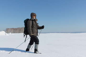 Fototapeta na wymiar Nordic Walking - adult man with a backpack hiking on snow in winter