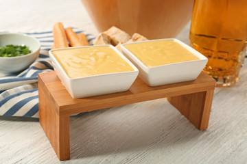 Bowls with beer cheese dip on wooden stand
