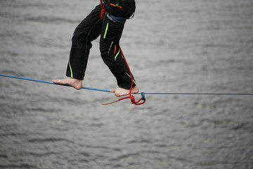 Fearless highliner walking on tight rope above the water