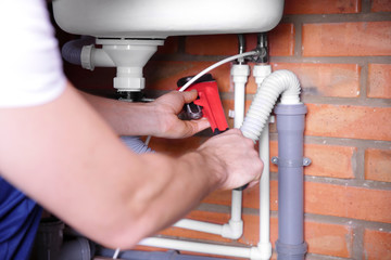 Plumber repairing sink pipes in kitchen, closeup