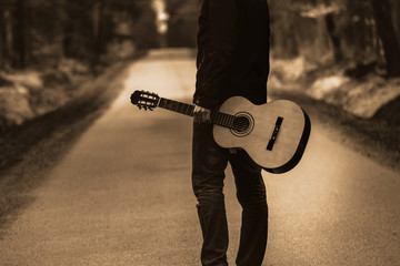 Fototapeta premium Osoba na ścieżce z gitarą. Bezpłatne podróżowanie z instrumentem country w lesie.