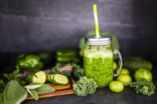 Healthy green smoothie in a mason jar mug on dark stone background. Vegetarian food and detox diet.
