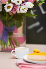 Cup of coffee, tasty cake and beautiful bouquet of flowers in cafe