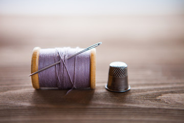 Vintage spool of thread with needle closeup. Tailor's work table, textile or fine cloth making.