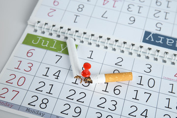 Broken cigarette pinned to calendar, closeup