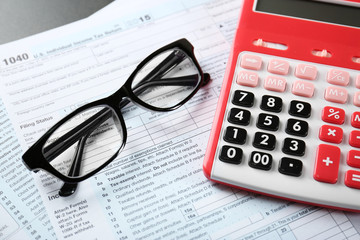 Calculator with documents and glasses on table. Tax concept