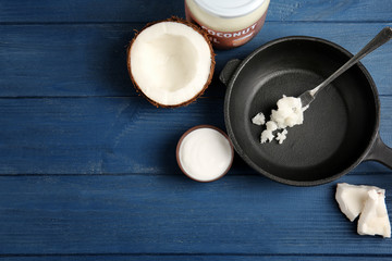 Coconut and kitchenware with fresh oil on dark blue background