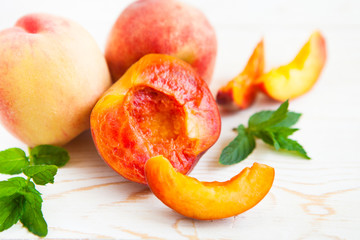 Fototapeta na wymiar Fresh peaches with mint on wooden white background.
