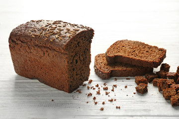 Sliced bread with seeds on white wooden background