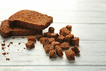 Slices and croutons of rye bread on white wooden background
