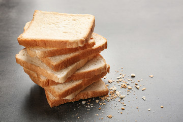Slices and crumbs of wheaten bread on grey background