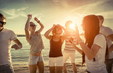 Friends funny dance on the beach under sunset sunlight.