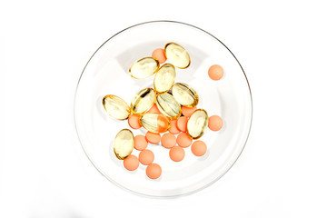 Red pills and capsules of cod-liver oil on glass stem