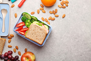 Lunch box with delicious food, fruits and almond on light textured background