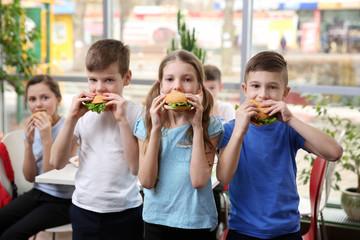Children eating hamburgers in school cafeteria