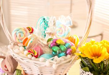 Colorful lollipops and eggs with traditional decorations in Easter basket on festive table