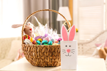 Beautiful Easter basket and cute gift bag on white table
