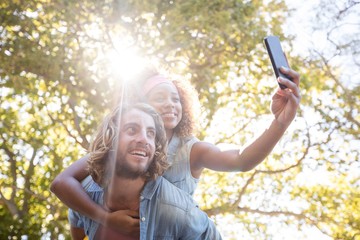 Couple taking selfie while enjoying piggyback ride
