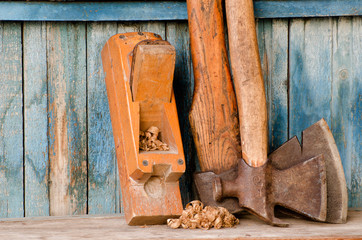 Old tools. Axe and plane on a vintage wooden background, with space for text