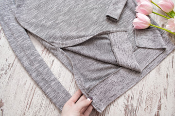 Inner part of a gray sweater, a female hand, tulips. Fashion element, top view