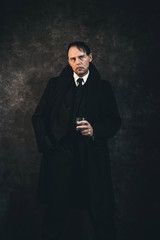 Retro 1920s english gangster holding glass of whiskey. Peaky blinders style.