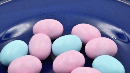 Close up of pastel pink and turquoise Easter eggs of chocolate and sugar on a blue plate. Suitable to be used like a background.