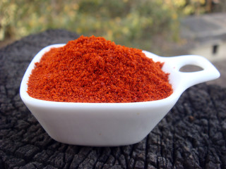 Red chilli powder in white bowl place on rusted wooden stack