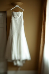 Wedding dress hang on white peg before the window