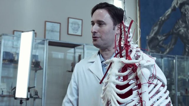 The professor showing the anatomy of a skeleton then ask one of student to show the same.