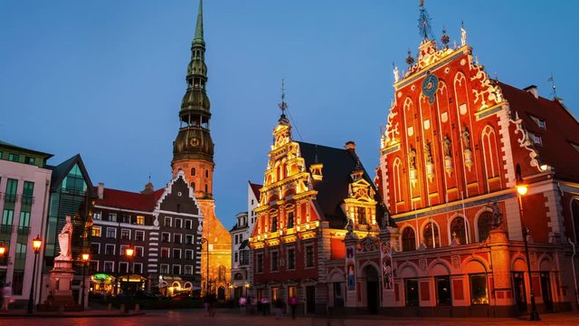 Riga, Latvia. House of the Blackheads and Cathedral in the old town of Riga, Latvia. Unidentified blurred people walking by the square at night. Time-lapse with sunset sky