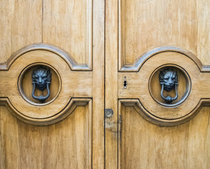  Lion head knockers on an old wooden door in Tuscany, Italy.
