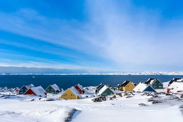 Fotobehang Yellow, blue, red and green inuit houses covered in snow at the fjord of Nuuk city, Greenland © vadim.nefedov