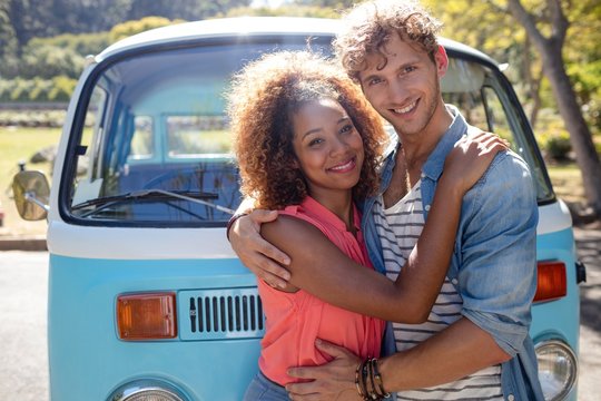Smiling couple standing in front of campervan