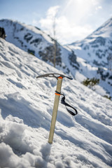 Ice axe stick in the snow in mountains
