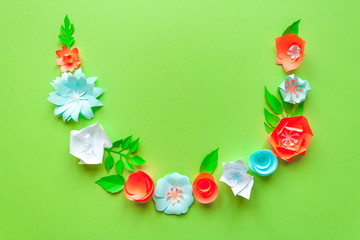 frame with color paper flowers on the green background. Flat lay. Nature concept. Cut from paper. Place for your text.