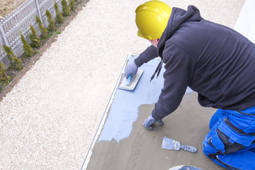 Industrial worker on construction site laying sealant for waterproofing cement. Worker apply liquid...
