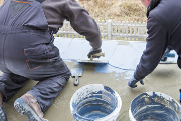 Industrial worker on construction site laying sealant for waterproofing cement. Worker apply liquid...