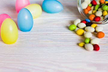 Candies and eggs on white wooden planks. 
