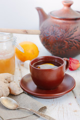 Nice ginger tea on white wooden surface.