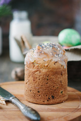 Easter cake standing on board against the basket with easter eggs.