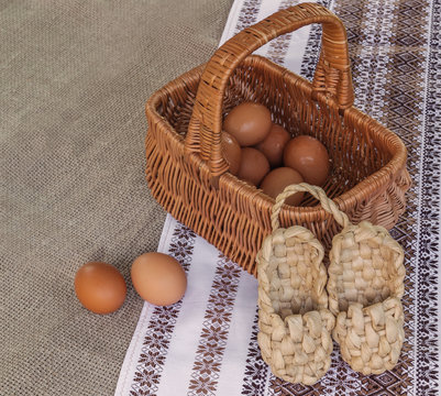 Rustic still life with basket with eggs and bast shoes