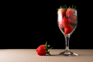 Strawberries in glass of wine on black background.